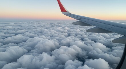 Obraz premium Airplane wing above clouds at sunset