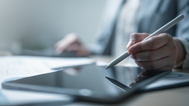 Close-up of businesswoman using stylus pen on digital tablet, symbolizing modern technology, online work, creative design, and smart business innovation.