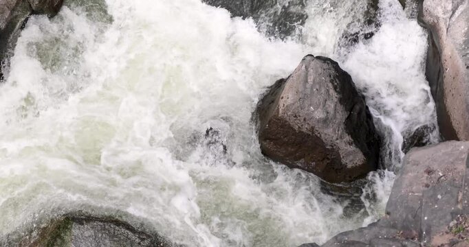 A large rock is in the middle of a rushing river