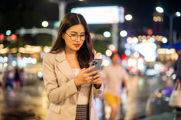 Businesswoman using smartphone on city street at night