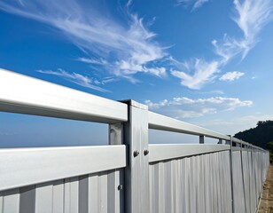 Fototapeta premium Metal fence against a bright blue sky with fluffy white clouds