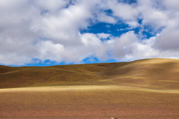 Obraz premium Desert landscape under blue sky with clouds and hills