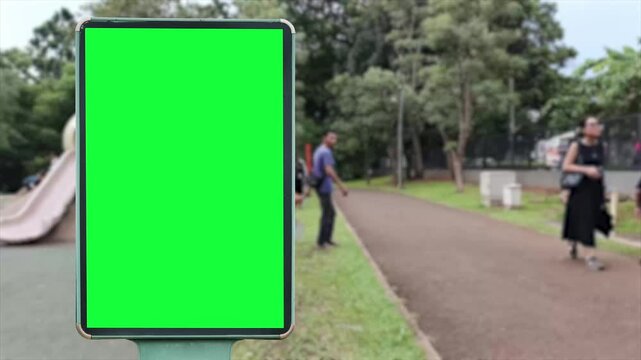 A wrinkled green poster template in the middle of an modern park where children play on slides and swings. A glued paper mockup. A blank city park art sticker mockup. A clear glued urban advertising