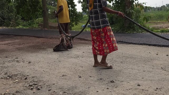 Road construction works going on in slow otion. Indian men working road maintenance. Road construction site in India. Road construction works going on in slow motion. Indian worker spraying primer.
