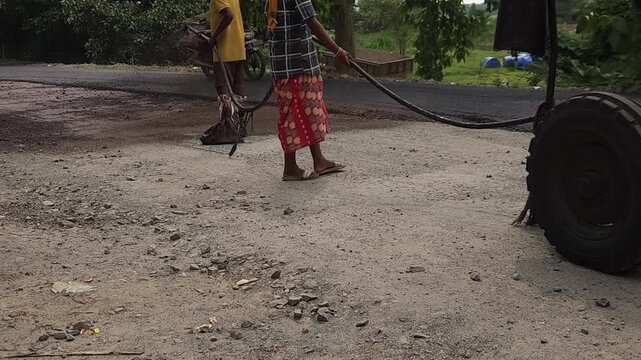 Road construction works going on in slow otion. Indian men working road maintenance. Road construction site in India. Road construction works going on in slow motion. Indian worker spraying primer.