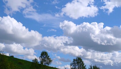 Obraz premium Lush green hill under a vibrant blue sky dotted with fluffy white clouds