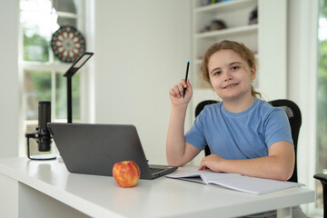 Kid studying at home with laptop and books. Child study online using laptop at desk. Studying with homework in child room. E-studying on laptop. Kid studying at home. Interior with kid and laptop.