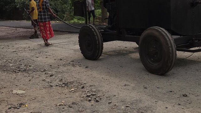 Road construction works going on in slow otion. Indian men working road maintenance. Road construction site in India. Road construction works going on in slow motion. Indian worker spraying primer.