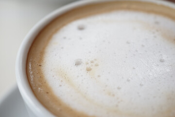 Delicious foamy coffee served in a white cup