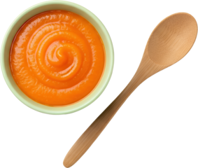 A bowl of vibrant orange puree with a swirl pattern sits next to a wooden spoon isolate food healthy