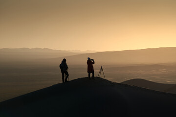 Silhouette of Two Photographers on Sand Dune in Desert during a Beautiful Sunset