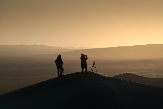 Silhouette of Two Photographers on Sand Dune in Desert during a Beautiful Sunset