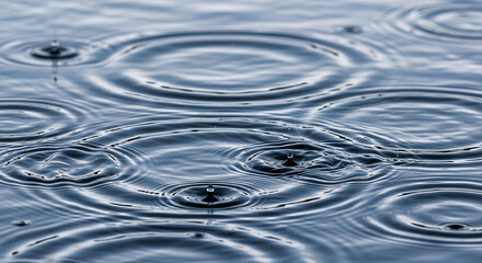 Close up of raindrops creating concentric ripples on the surface of water