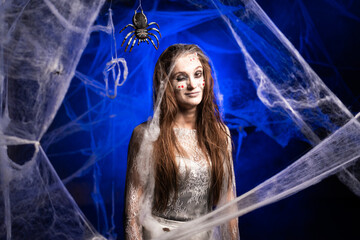 sinister woman in white dirty dress with horrible Halloween zombie makeup smiling looking at camera...