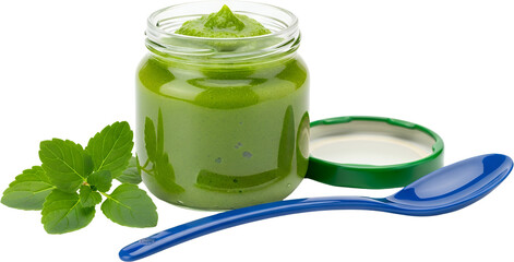 A glass jar filled with green baby food a blue spoon and mint leaves isolate green food puree infant food