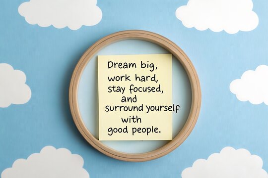 Circular wooden frame displays motivational quote against a whimsical cloudy sky background
