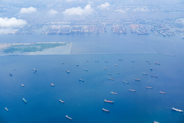 Dozens of cargo ships line the northern Jakarta waters with a vast port in the distance, capturing...