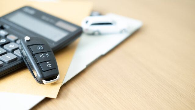 Black car key with calculator and toy car on documents representing auto loan calculation car insurance financial planning vehicle investment and transportation security.