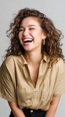 Joyful Gen Z fashion model with a bright smile and curly hair, laughing against a neutral backdrop. 