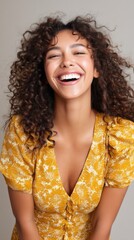 Joyful Gen Z fashion model with a bright smile and curly hair, laughing against a neutral backdrop. 