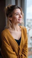 Relaxed young woman in a cozy apartment, looking out the window with a serene smile. 