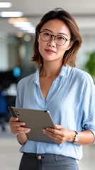 Successful Chinese fintech employee reviewing digital reports on tablet in office. 