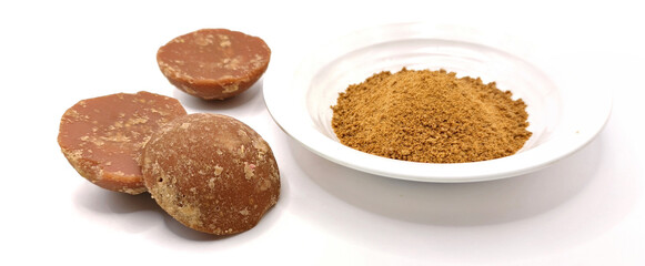 three pieces of natural brown palm sugar or coconut sugar in semicircular shapes and in powder form in white plate isolated on white background