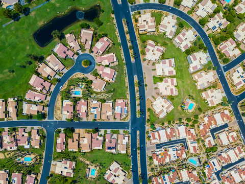 Aerial view of luxury residential homes and tennis courts in Palm Desert, California, surrounded by golf courses and dry mountains