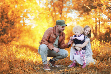 Fototapeta premium Girl walking in the autumn park. Autumn in the city, girl with dad for a walk. Parents are walking with little children. Autumn park people