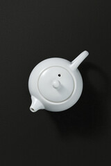 White ceramic teapot on a dark textured background