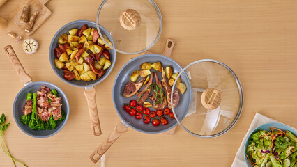 Bowls with meat, potatoes and vegetables on a wooden table