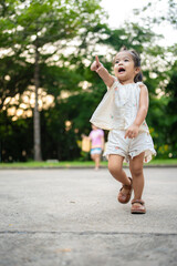 Preschool little asian girl enjoy walking on city pathway public park tree forest