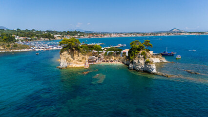 Aerial view of Cameo Island Zakynthos Greece with emerald clear sea rocky cliffs and green pine trees against blue Mediterranean horizon