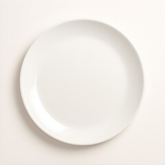 Simple round white dinner plate on a clean white surface overhead view