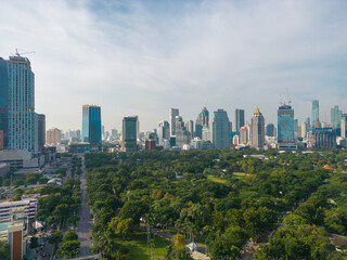 Obraz premium Aerial view green tree forest Lumpini public park with modern office building agiant blue sky cloud