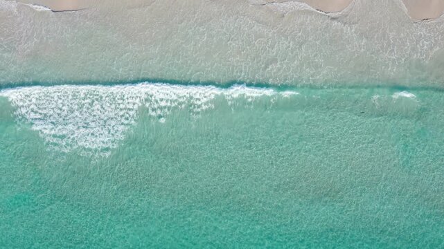 Aerial top down of foamy turquoise waves on a white sand Snelling Beach, Kangaroo Island, South Australia