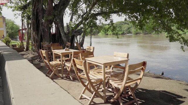 Peaceful outdoor cafe with empty wooden tables and chairs on the banks of the magdalena river