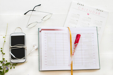 notebook, mobile phone and calendar for planner business work arrangement flat lay style on background white