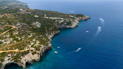 Blue Caves Zakynthos Greece top view of natural cave entrance rocky peninsula turquoise Ionian Sea and boats floating close to the coastline
