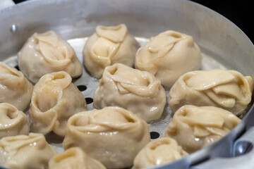 Delicious Manty, posture, khinkali is prepared in a special pot - mantoverde. Dishes of Asian, Buryat, Georgian cuisine. Aluminum steamer for cooking mantas on a stove in a home kitchen. Meat food.