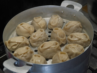 Delicious Manty, posture, khinkali is prepared in a special pot - mantoverde. Dishes of Asian, Buryat, Georgian cuisine. Aluminum steamer for cooking mantas on a stove in a home kitchen. Meat food.
