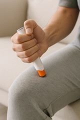 A person administers an epinephrine auto-injector into their thigh, demonstrating a life-saving action for a severe allergic reaction or anaphylaxis