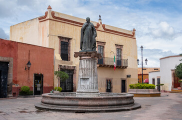 Fototapeta premium A statue of a woman stands in front of a building. The statue is surrounded by a fountain. Historic center of Queretaro City, decorations and traditions to celebrate Mexico's Independence Day, colonia