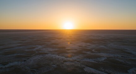 Fototapeta premium Sunset over a vast, frozen expanse with reflective ice and calm horizon