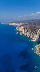 Aerial view of dramatic Zakynthos coastline with towering limestone cliffs turquoise coves deep blue Ionian Sea and rugged dry hills above shore