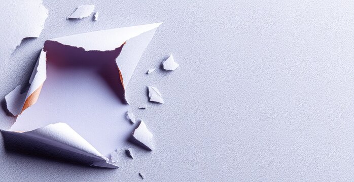 Ripped paper revealing a light area on a pale lavender surface