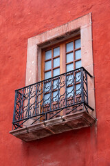 Fototapeta premium A window with a wooden frame and a metal railing. The railing is ornate and the window is open. Historic center of Queretaro City, decorations and traditions to celebrate Mexico's Independence Day, co