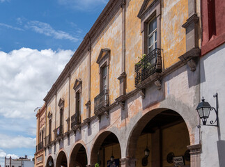 The building has a lot of windows and is yellow. The windows are open. Historic center of Queretaro City, decorations and traditions to celebrate Mexico's Independence Day, colonial architecture, alle
