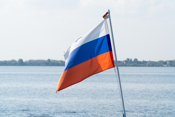 The Russian flag flutters in the wind against the blue sky. The national flag of Russia waving in the wind on a clear day. White, blue and red horizontal stripes. Russian Federation flag. 