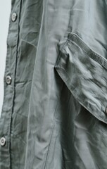Close-up of a sage green, long-sleeved button-down shirt showcasing its lightweight, subtly textured fabric and a patch pocket on the sleeve